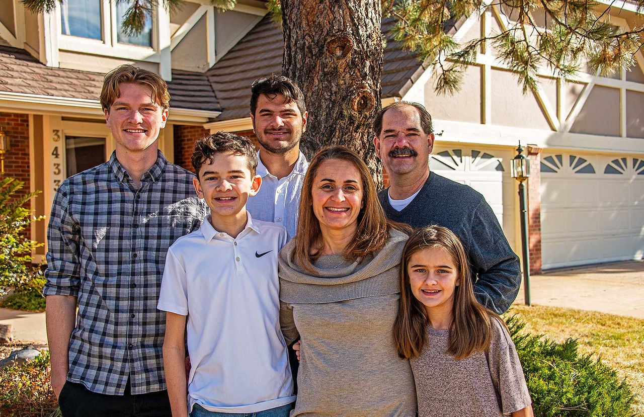 Seattle general manager Jila Javdani, wearing a dark beige sweater, standing with three men, a boy, and a young girl outside of a home.