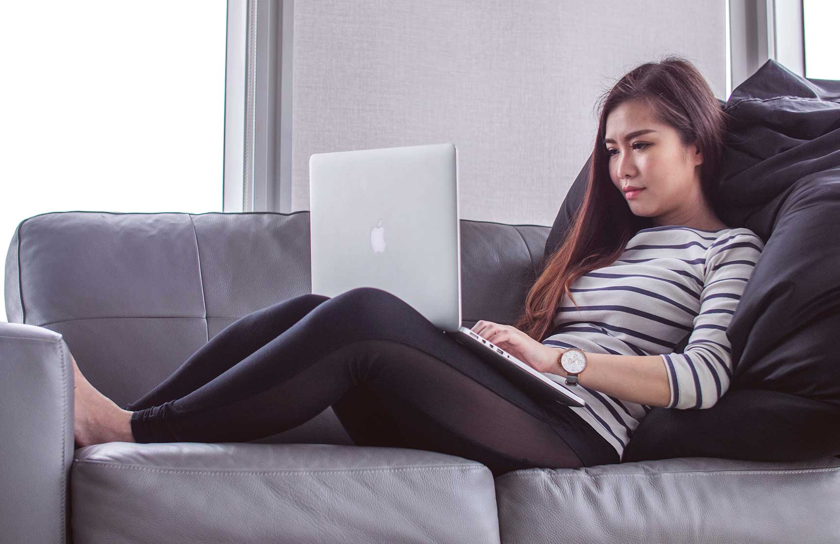 Woman on couch working on laptop.