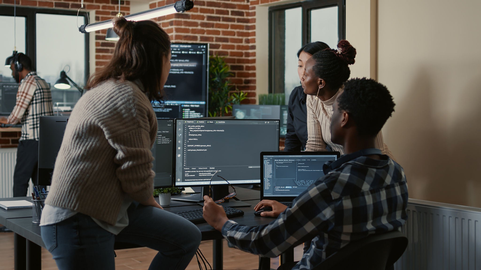 Software developers discussing about cloud programming innovation while the rest of the team joins the discussion. Programmers doing teamwork computing big data in server room.