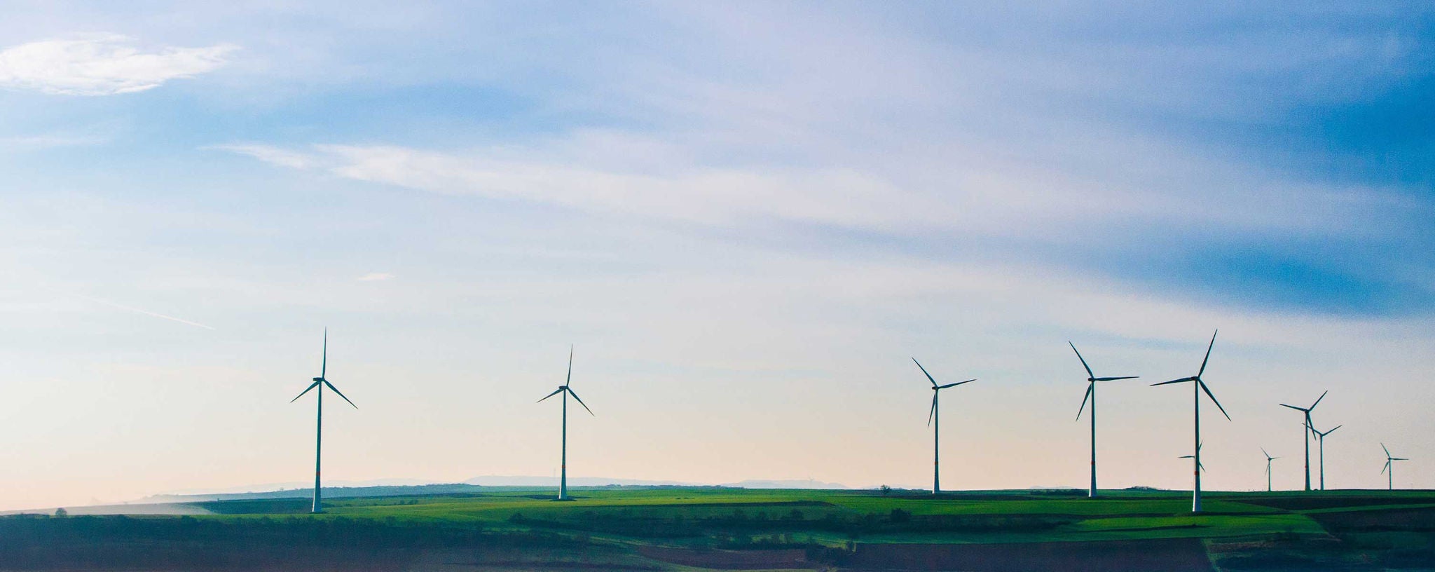 Windmills dot a rolling green landscape.