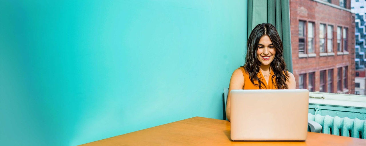 Woman working on computer in kitchen.