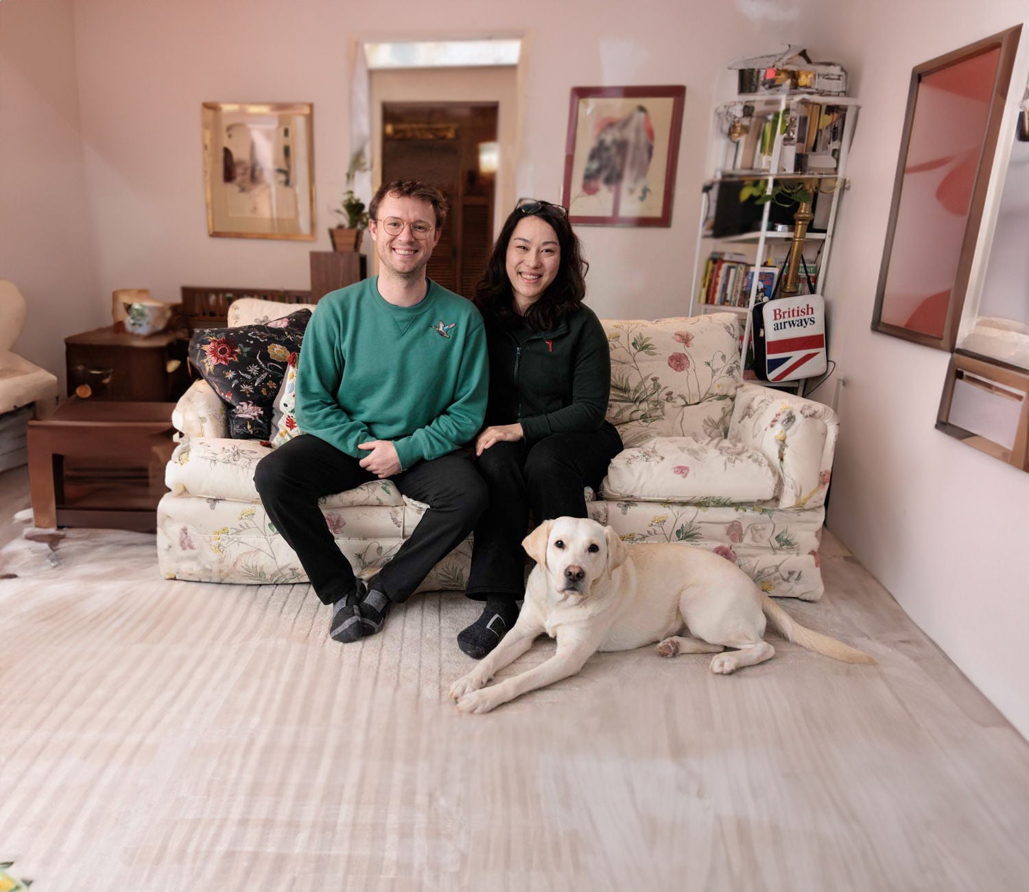 Ein Paar sitzt auf dem Sofa mit einem Hund zu ihren Füßen