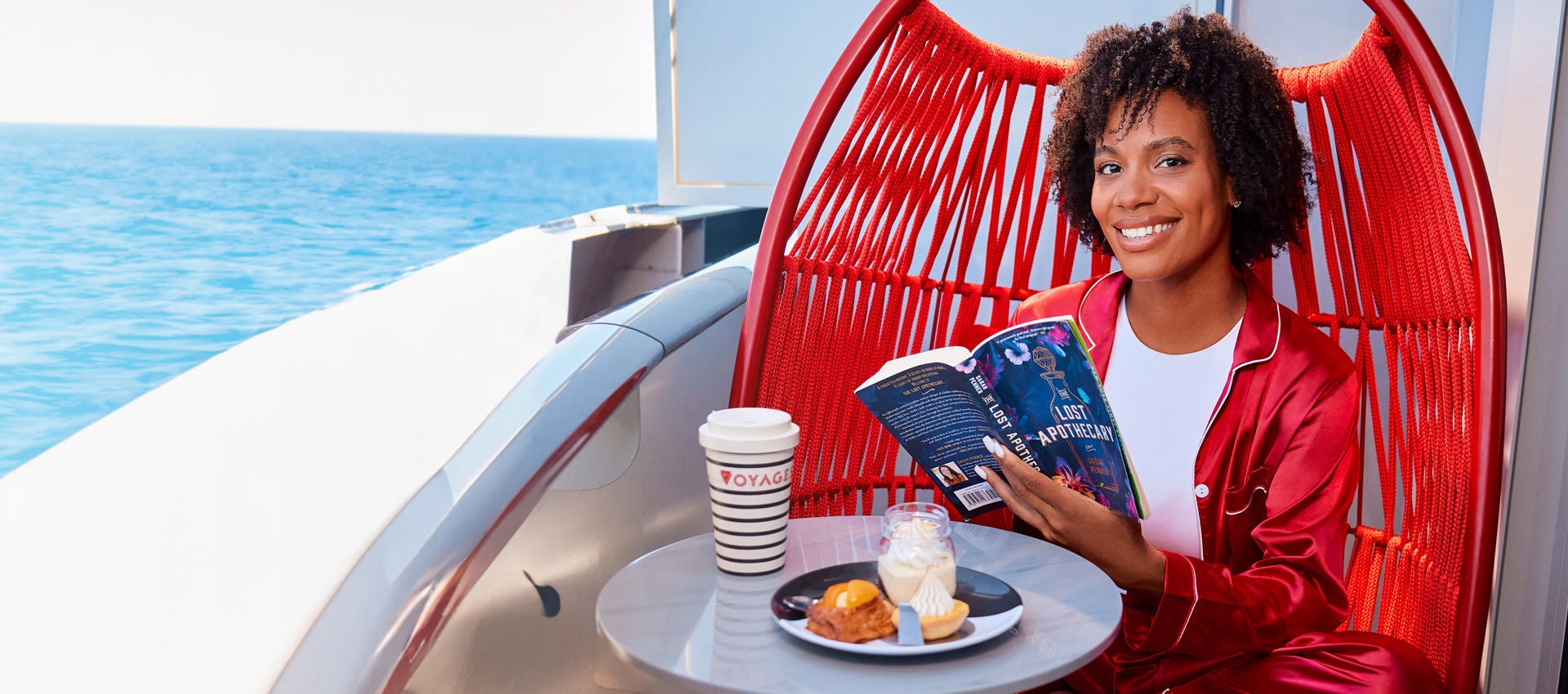 A happy and relazed Virgin Voyages passenger starts their day with breakfast and reading.