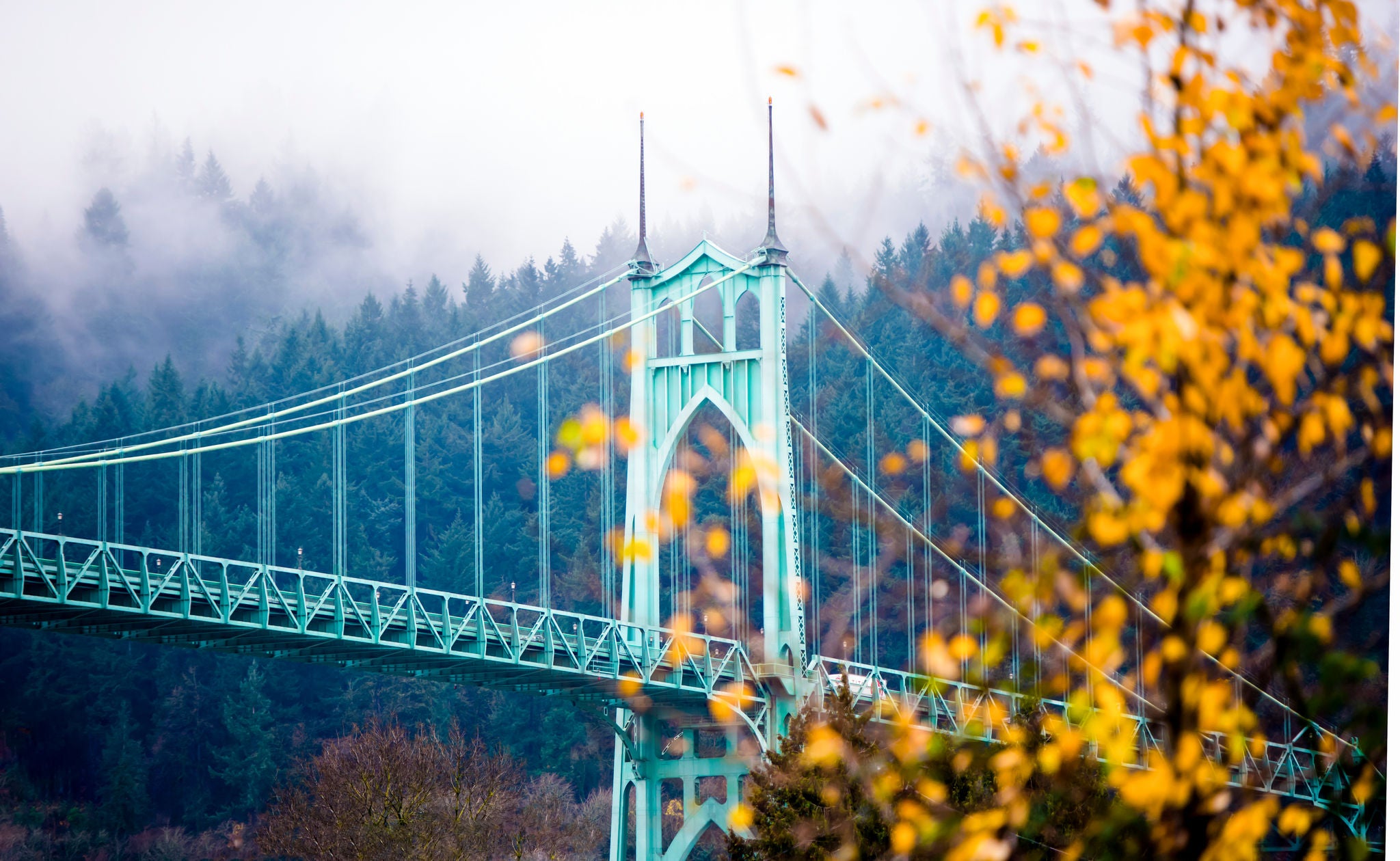 Gothic style arches tracery St Johns bridge Portland Oregon in the morning mist decorated with autumnal yellowed trees.