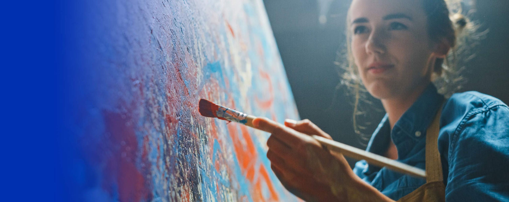 Woman painting on a canvas full of blotches of different colors.