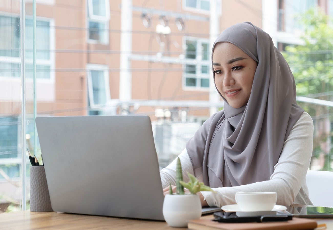 A woman works on a laptop from a bright modern office space.