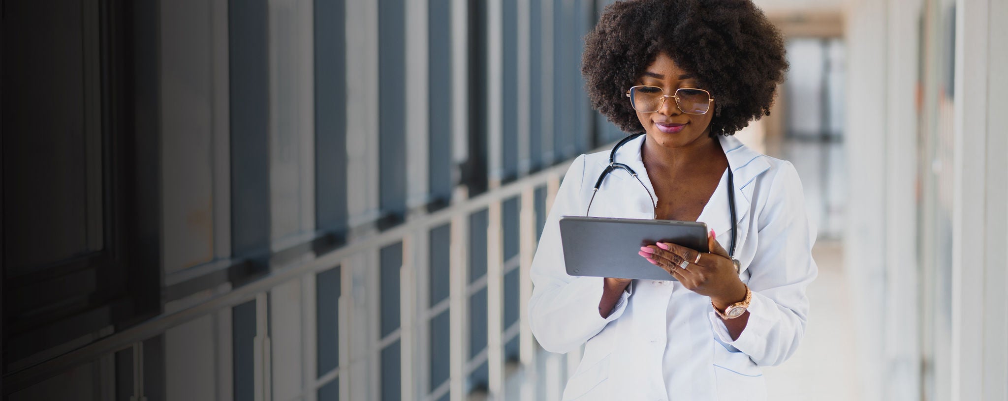 Doctor standing in hallway with digital tablet.