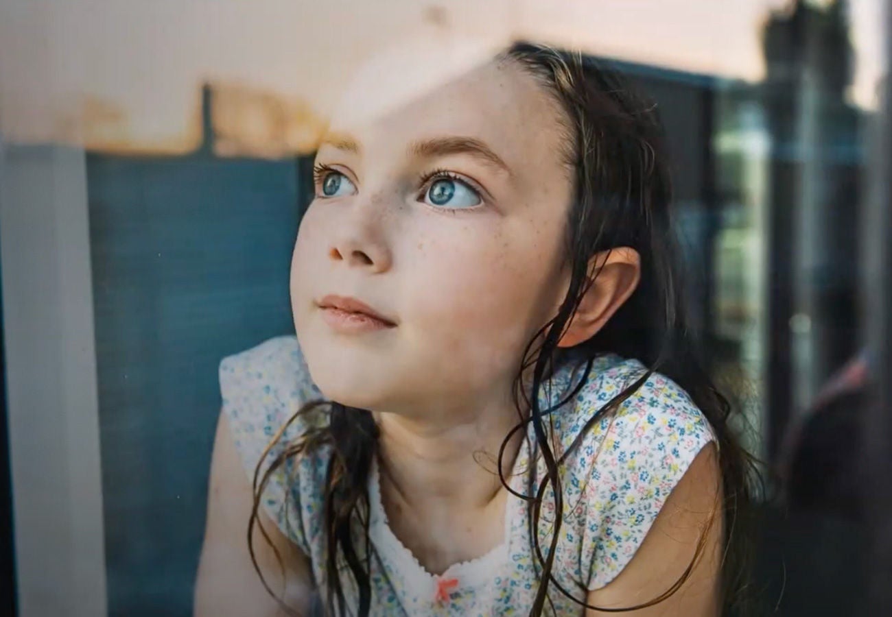 A girl looks out a window towards the sky.