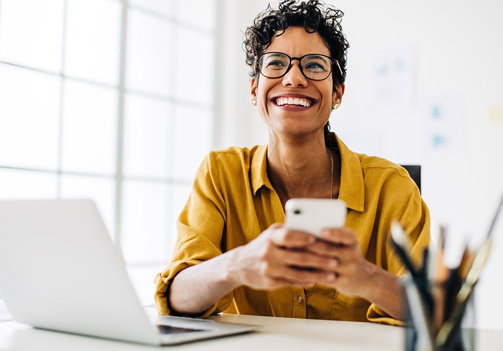 Professional black woman smiling and using a mobile phone Professional black woman smiling and using a mobile phone