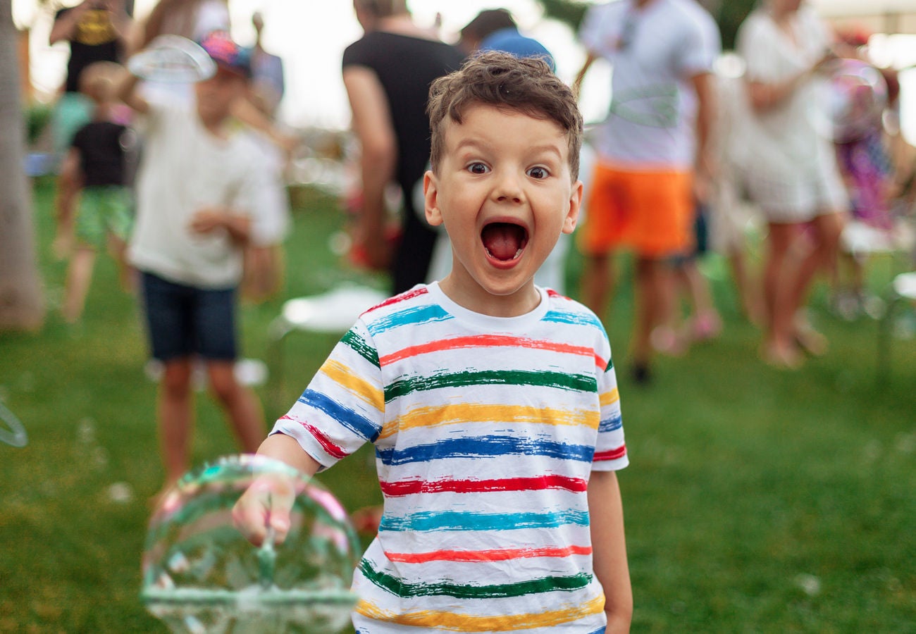 A happy young child makes bubbles at a family gathering.