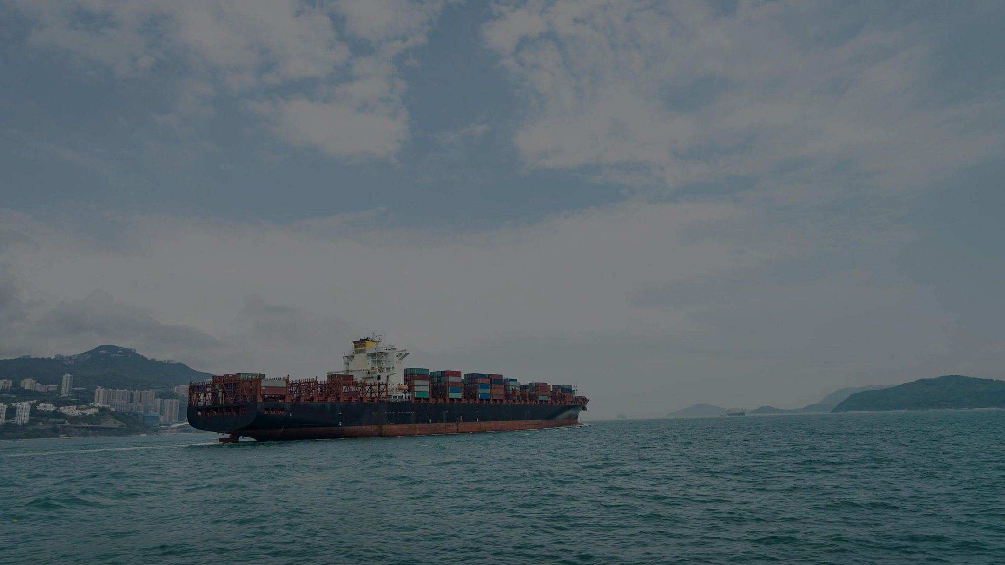 Cargo container ship in transit along coastline.