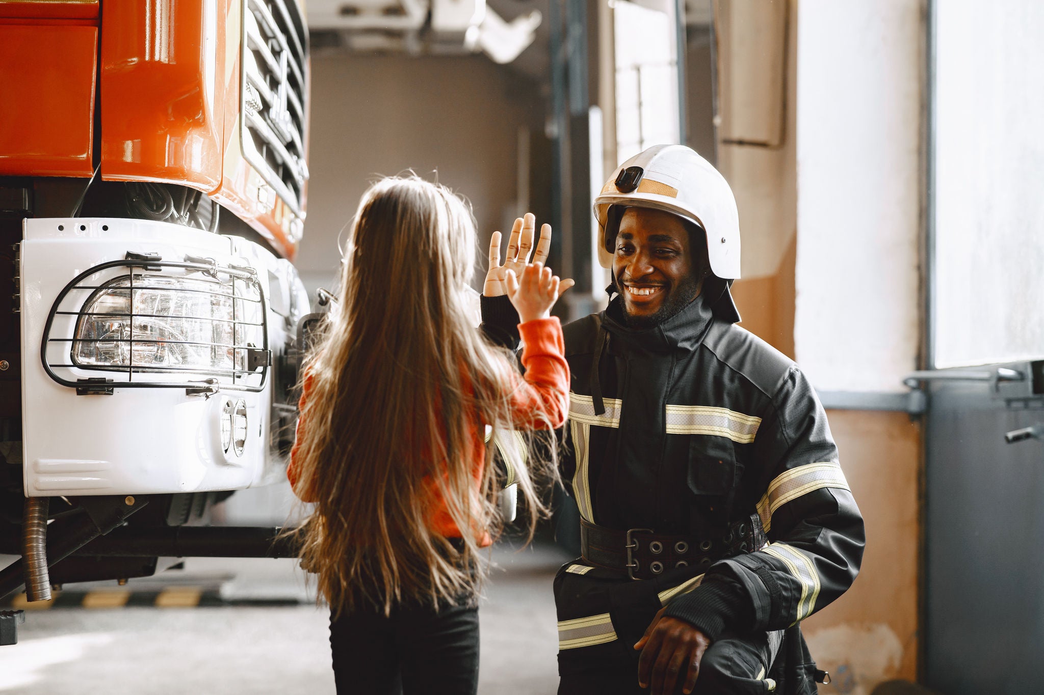 Fire fighter giving youg girl a high-five