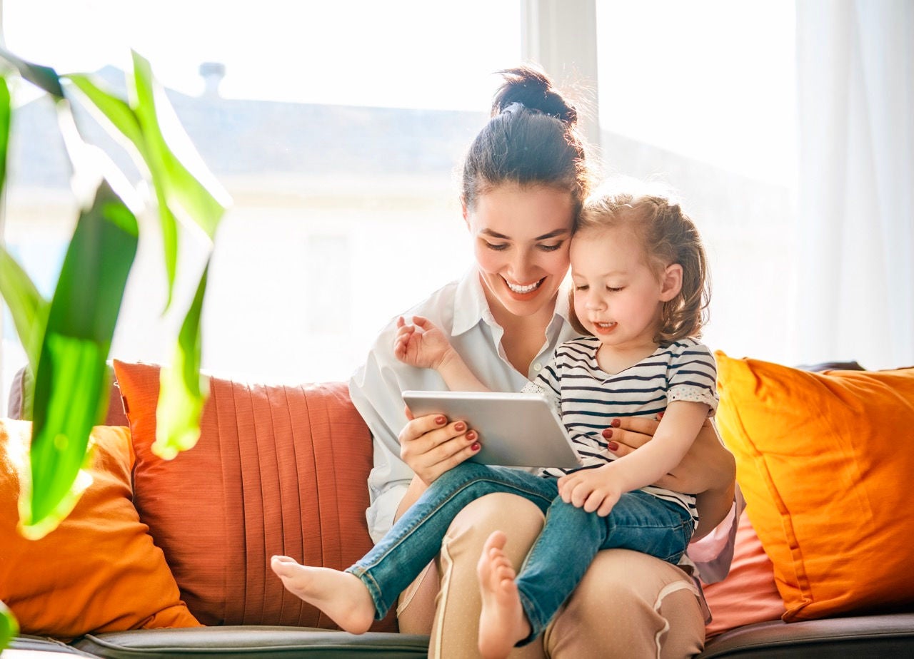 Happy loving family. Young mother and her daughter girl play in kids room. Funny mom and lovely child are having fun with tablet.