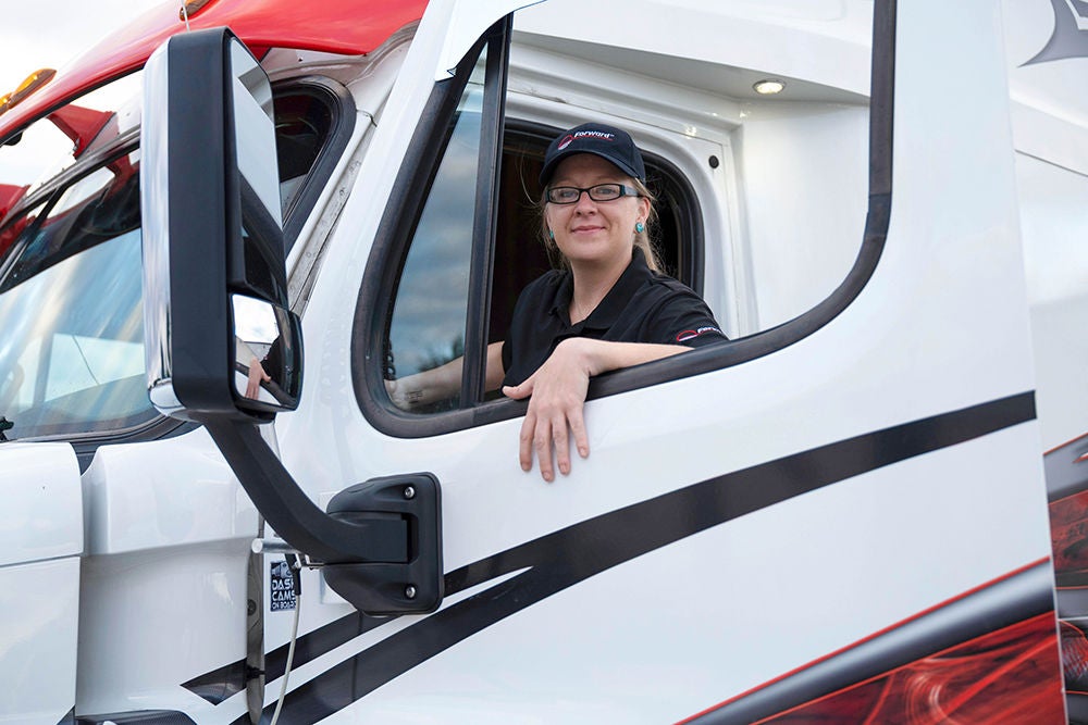 Woman trucker stepping into her truck.