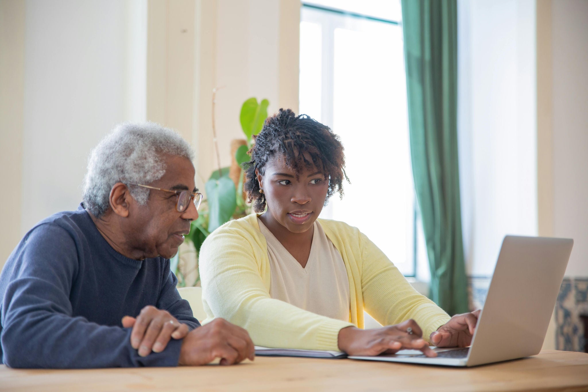 young woman helping older man at laptop