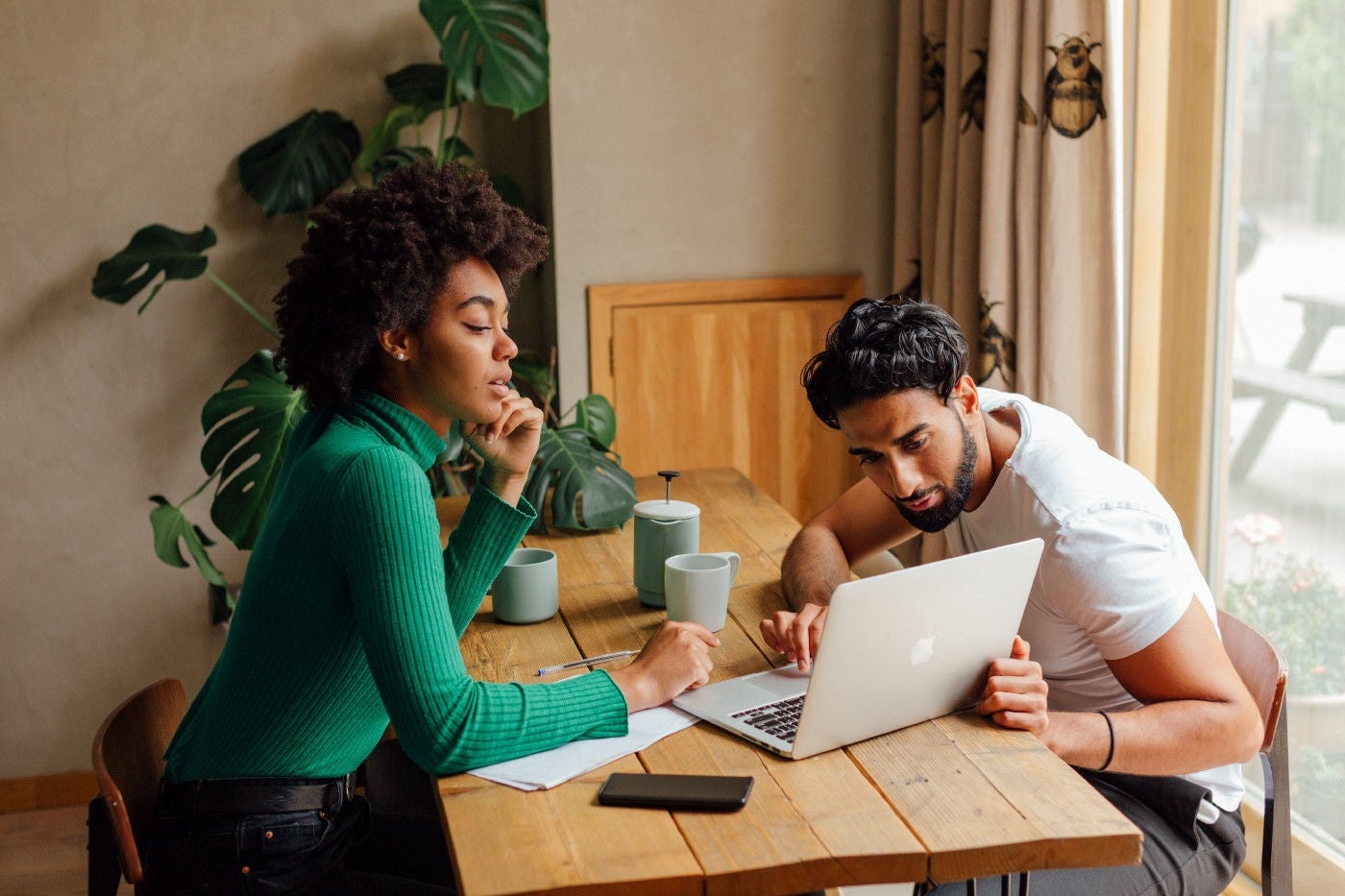 A man and woman looking at laptop, while having coffee.