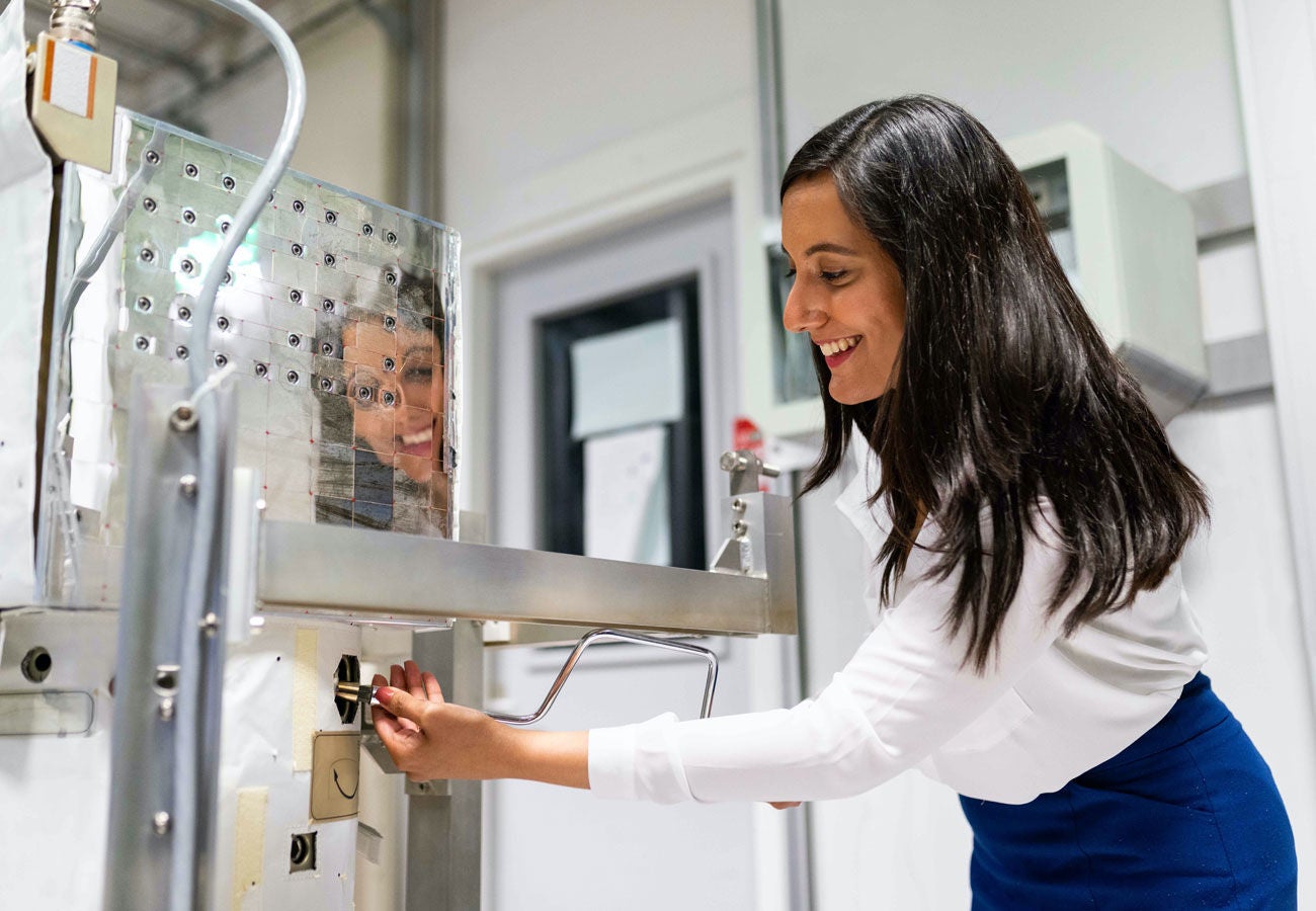 Woman smiling and leaning over to work on machine