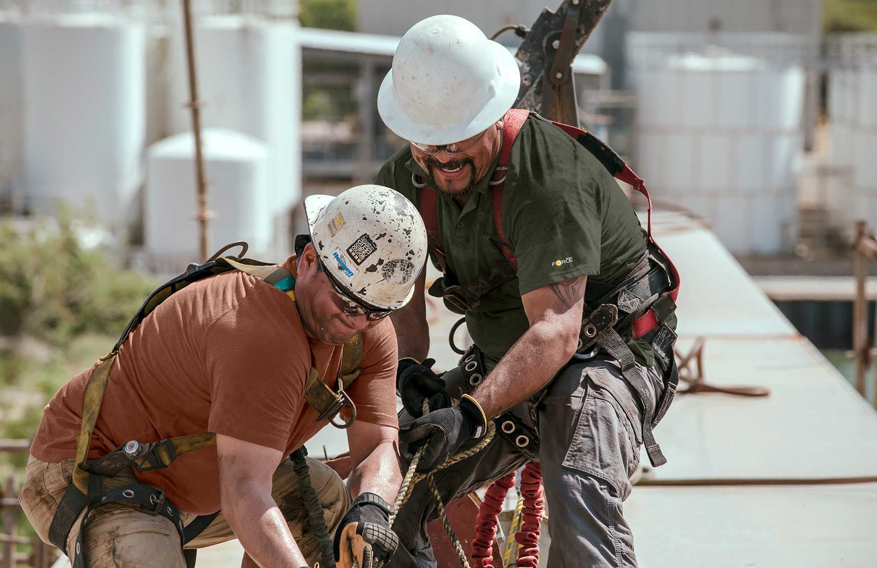 Two construction workers shown pulling on ropes