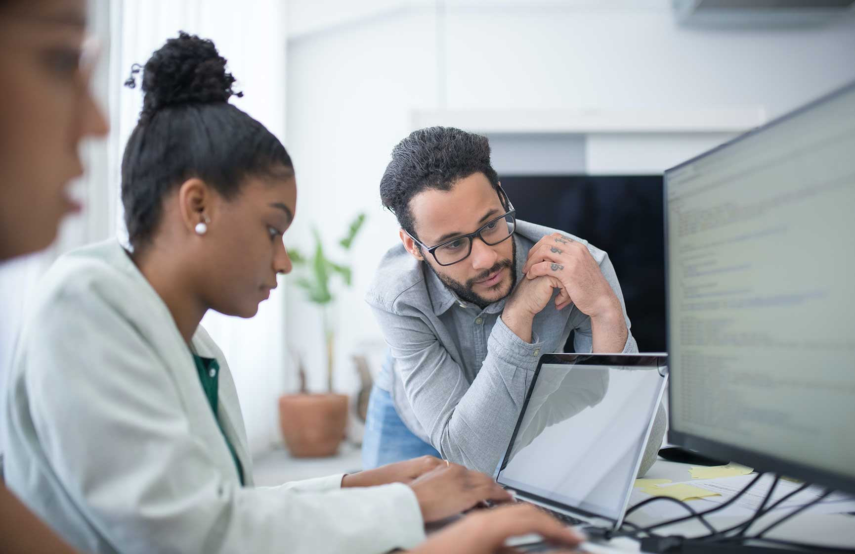 A woman working on her laptop with her colleague.