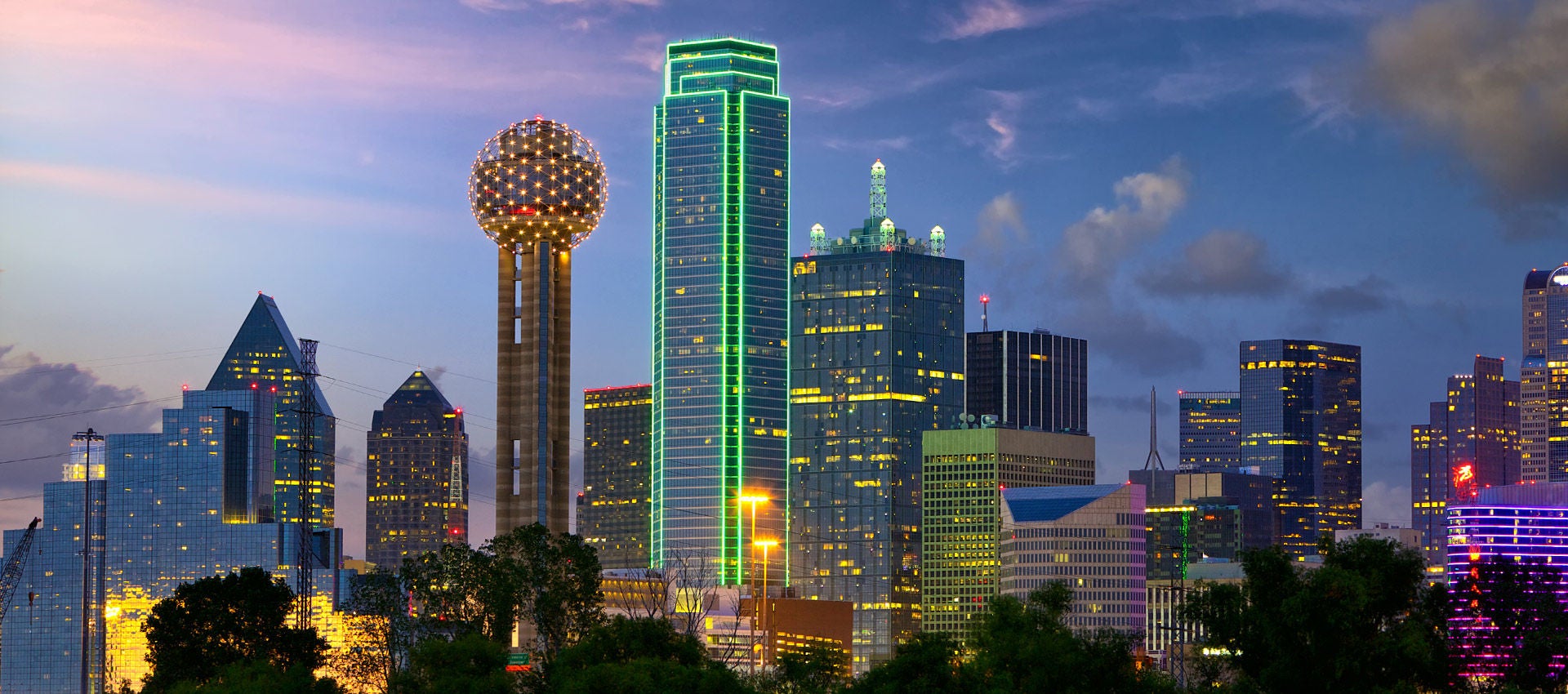 The Dallas skyline lights up as dusk fades across the city. 