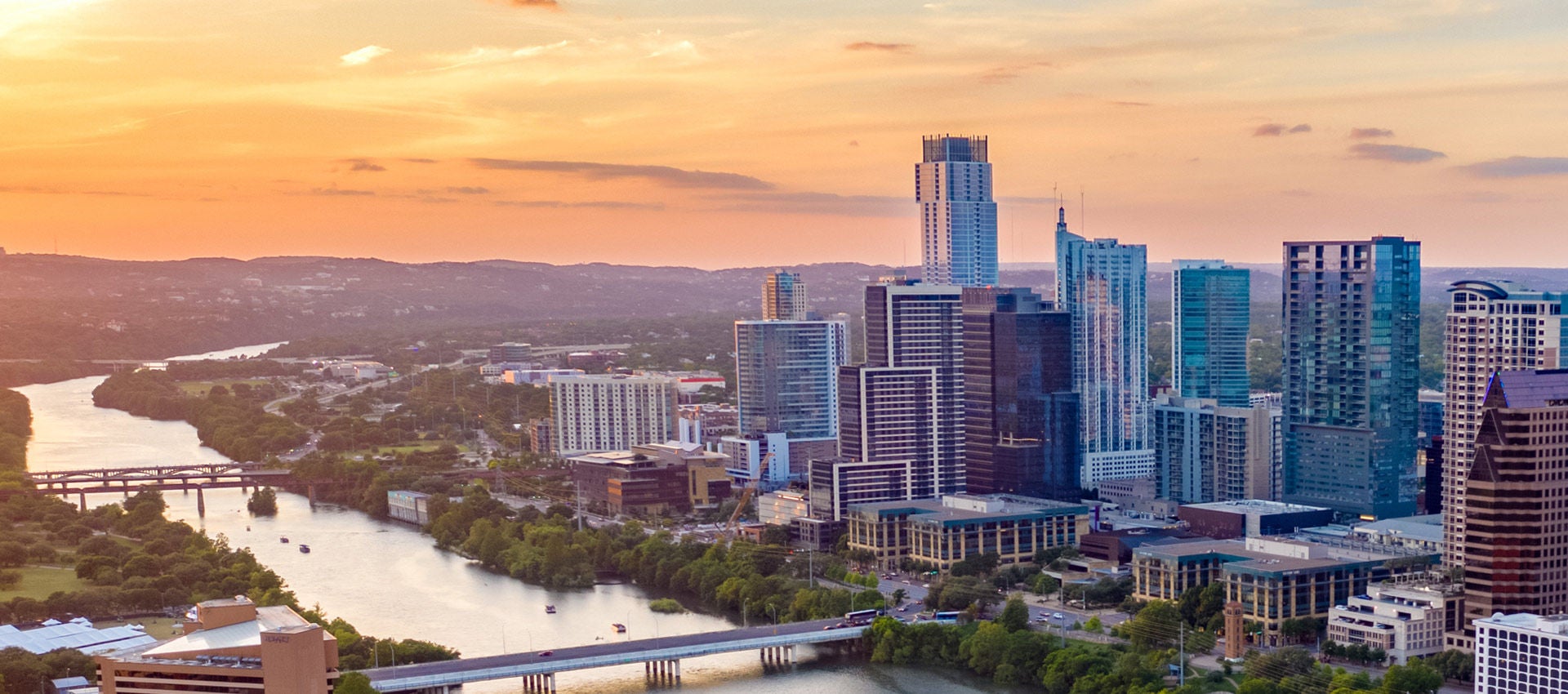 The sun sets on the Colorado River and the city of Austin, Texas.