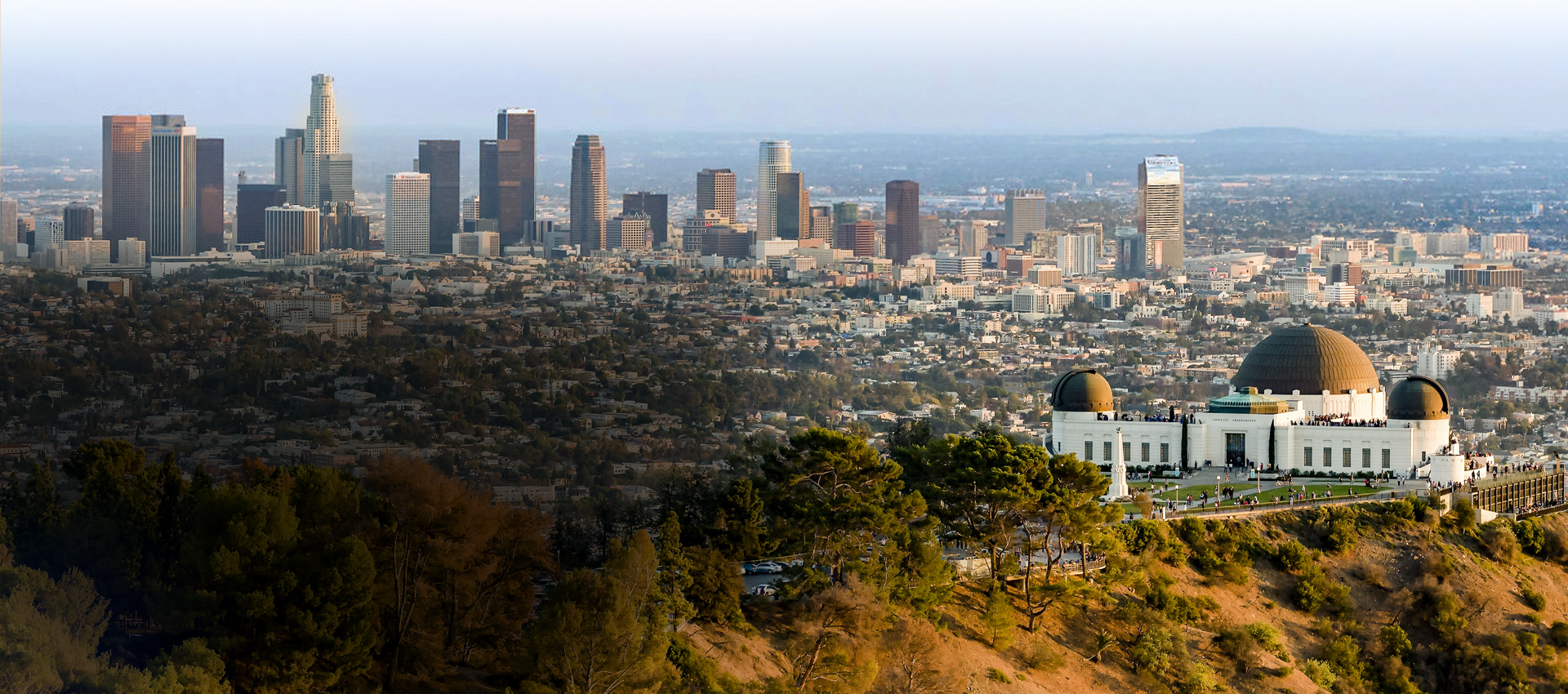 The Griffith Observatory sits in front of the Los Angeles skyline and city below the hill.