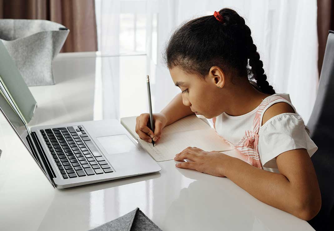Little girl studying at home with her laptop. 