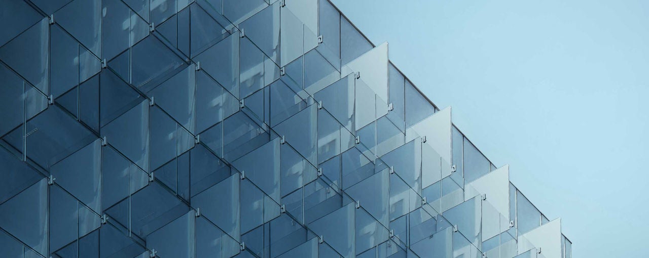 Image of geometric glass building and blue sky.