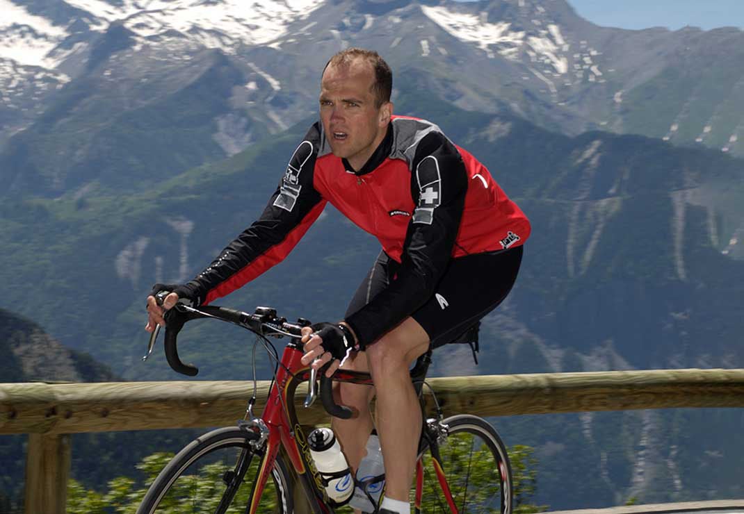 Slalom General Manager Todd Christy biking with mountains as backdrop.