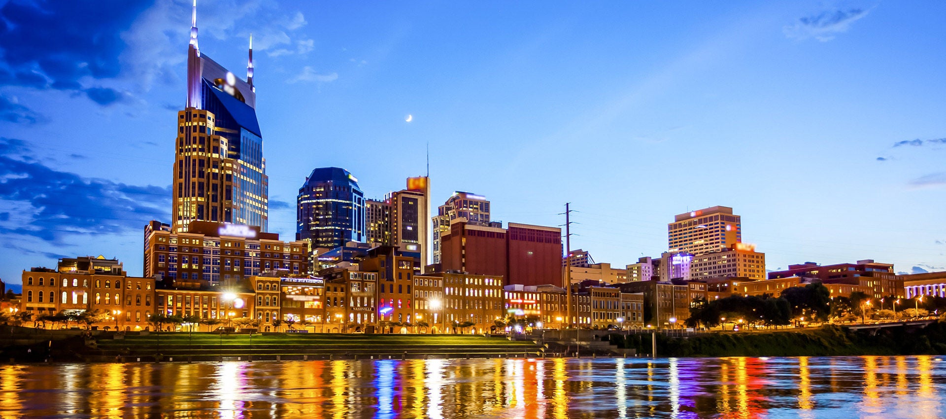 The Nashville skyline lights along the river up as dusk fades into the night. 