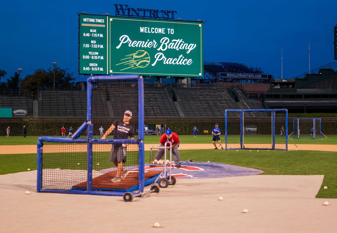 A baseball fan and a Slalom group, learning how to pitch at the annual Batting Practice at Wrigley Field.