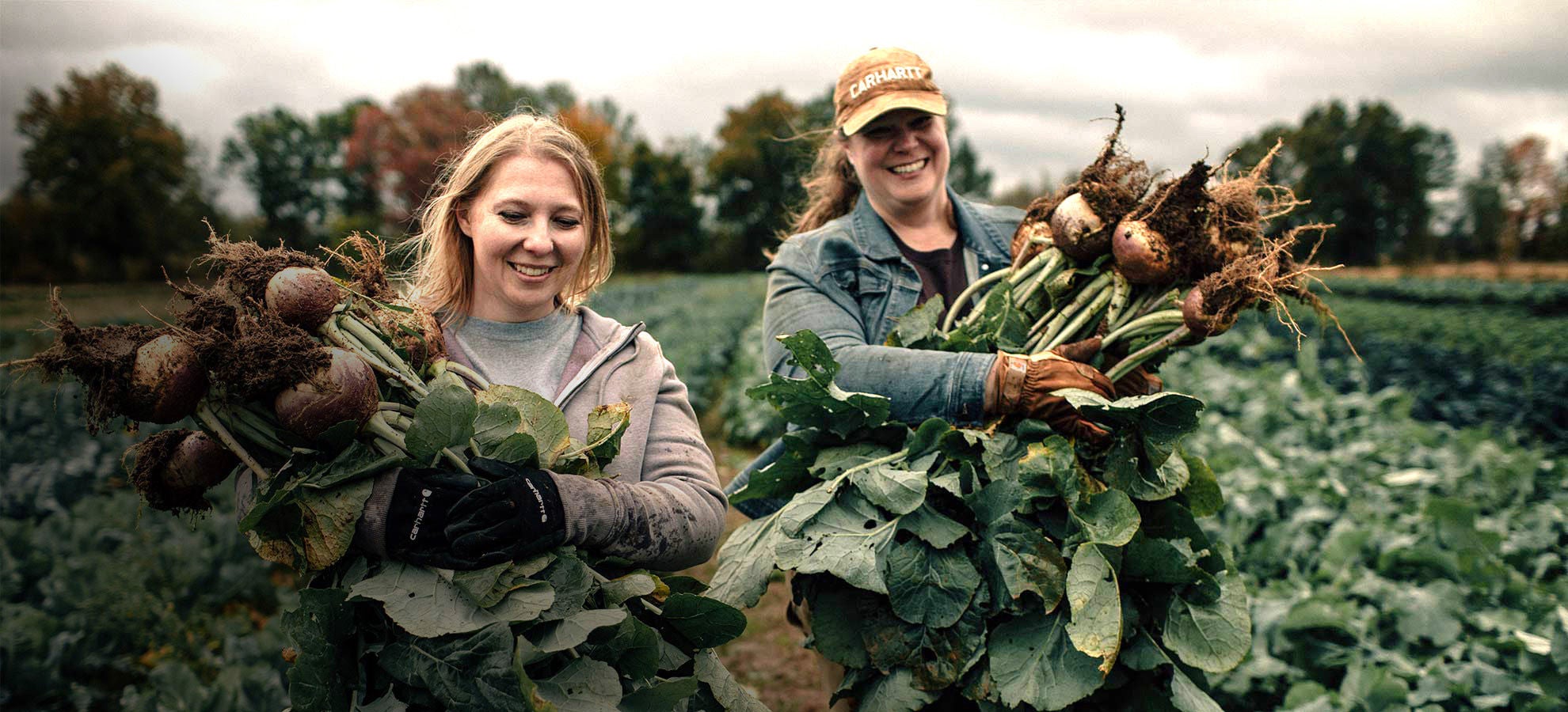 two women farmers holding crops