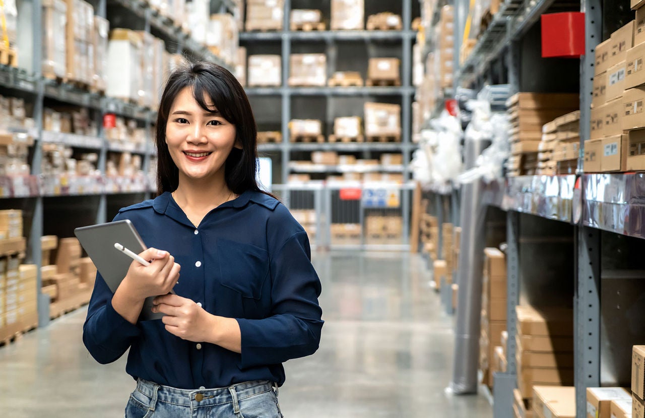 Woman worker inside a warehouse holding a clipboard.