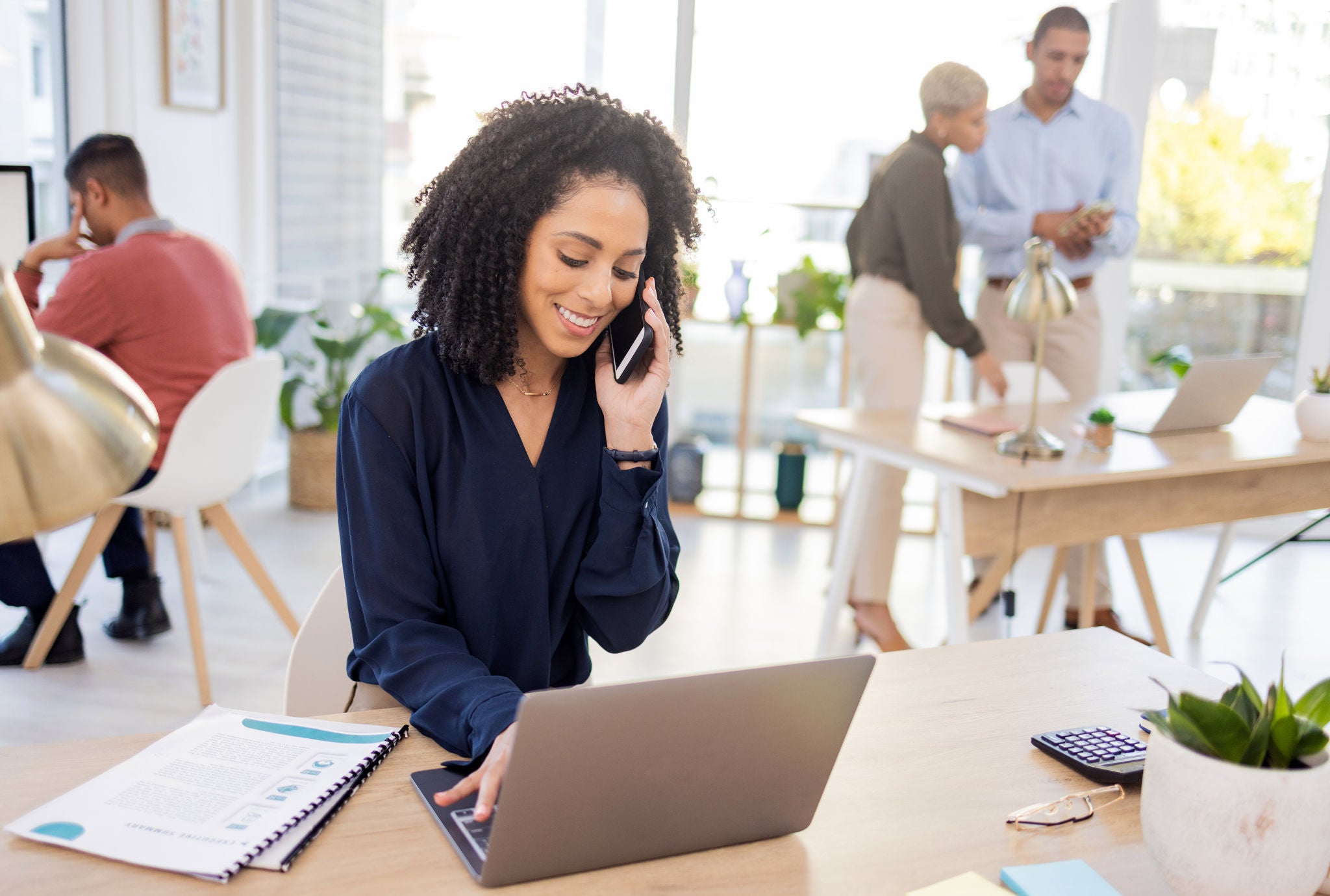 Black woman, phone call and laptop in office for communication, information and marketing. Entrepreneur person at advertising agency while talking to contact for proposal deal or networking at desk.