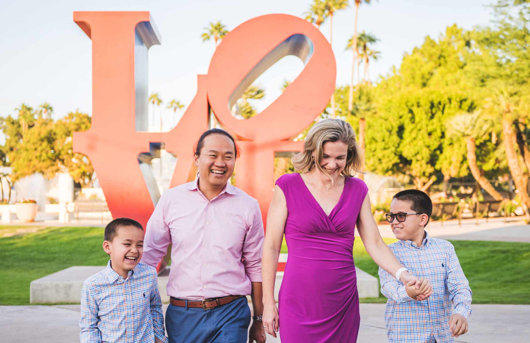 Phoenix general manager Sarah Moesker in a fuchsia dress, walking with her husband in a pink button-down shirt and their two children in plaid button-downs at their sides.