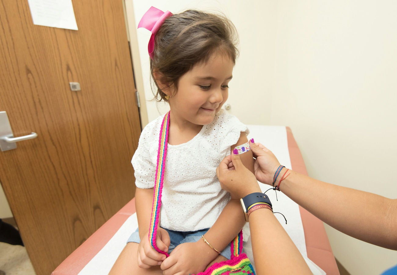 A young girl has a band-aid applied at a health clinic. 