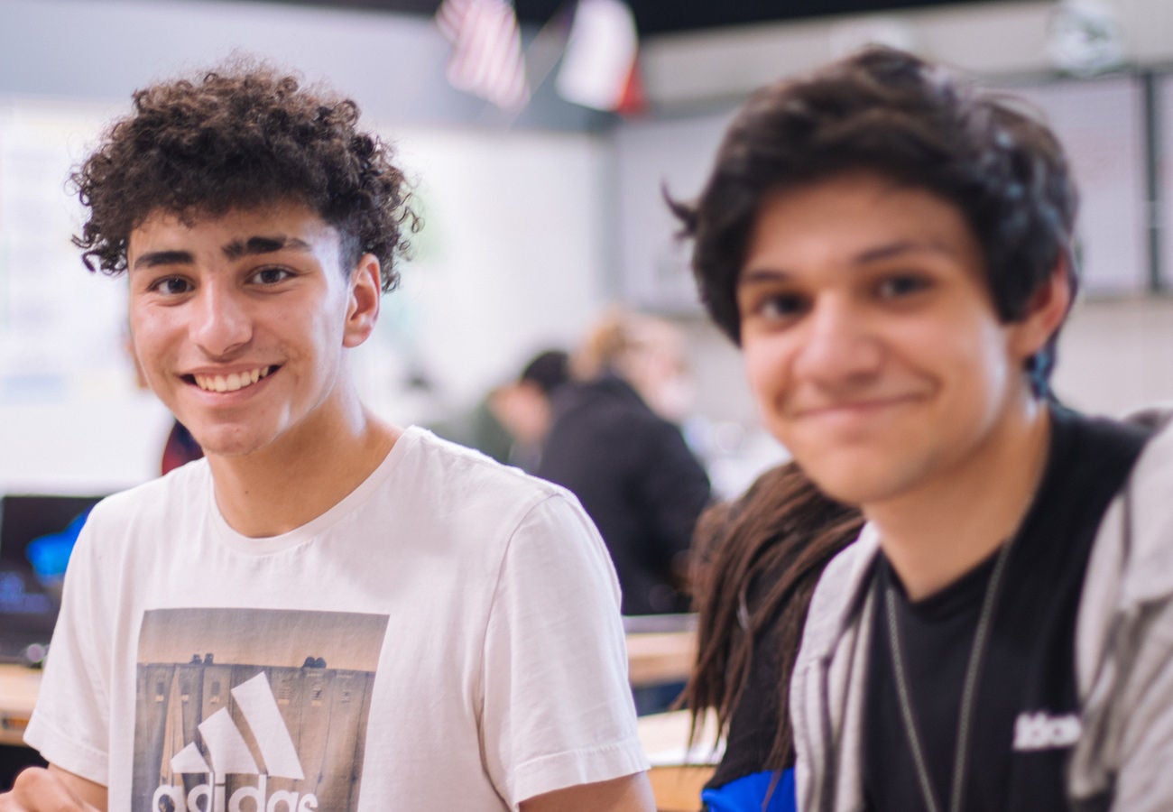 Tow students smile in a classroom.