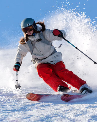 Person skiing downhill with poles and red ski pants